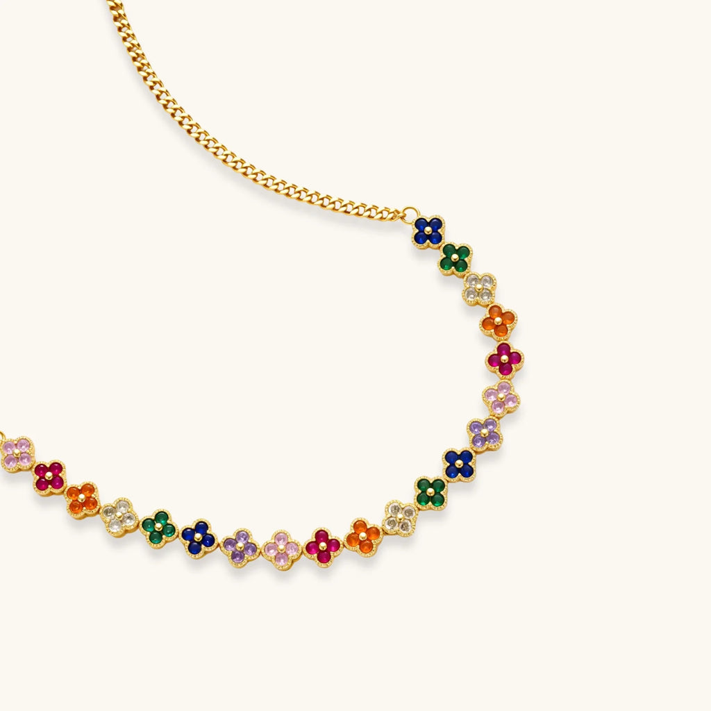 Colorful four-leaf clover jewelry set with rainbow cubic zirconia stones in gold-plated setting on white background