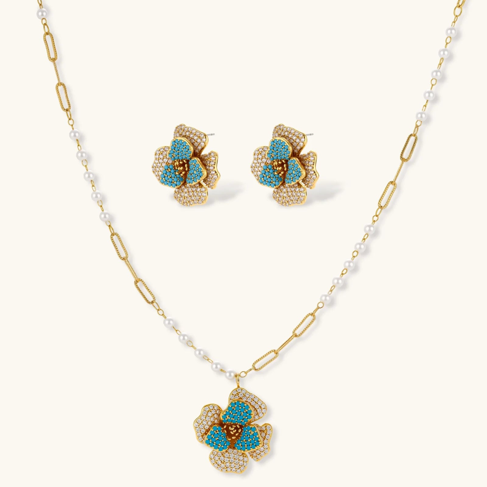 14K gold-plated floral jewelry set with blue cubic zirconia centers and pearl chain details on white background.