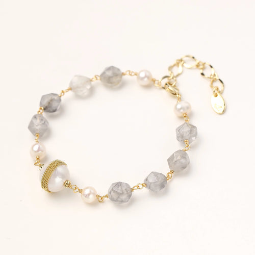 Bracelet with cloudy quartz beads, freshwater pearls, and gold-wrapped baroque pearl centerpiece on white background.