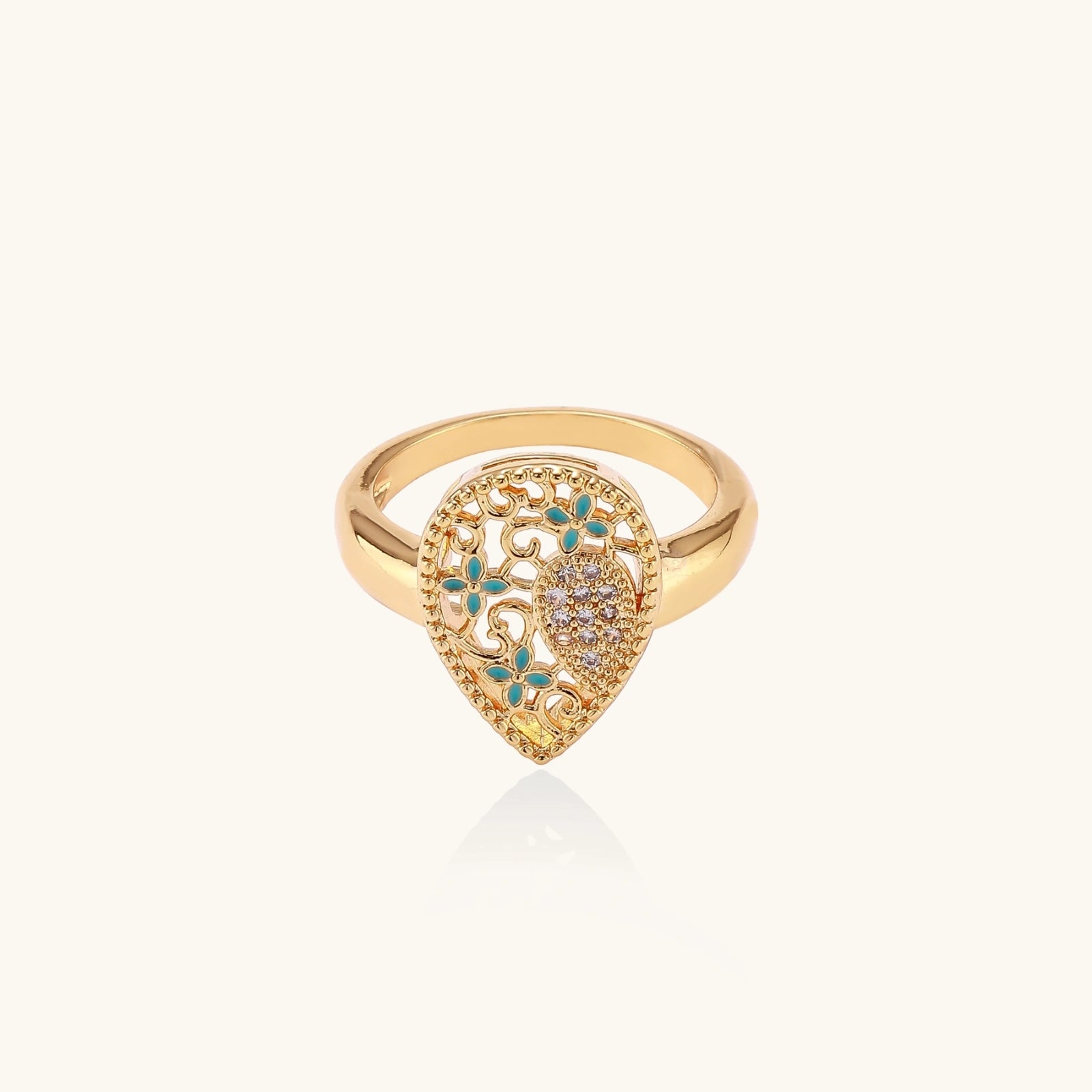 Teardrop-shaped gold-plated ring with turquoise enamel flowers and crystal pavé detail on cream background