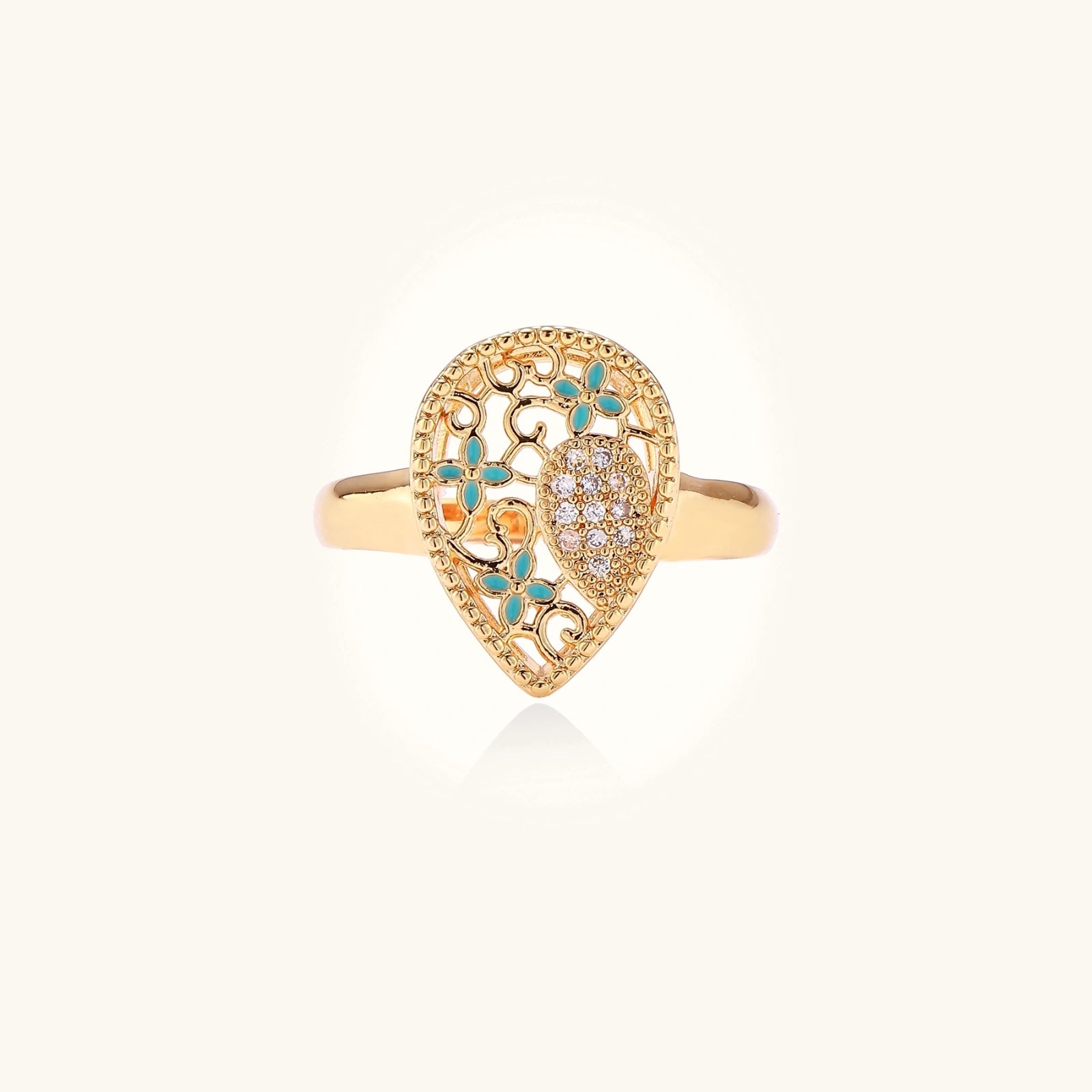 Teardrop-shaped gold-plated ring with turquoise enamel flowers and crystal pavé detail on cream background